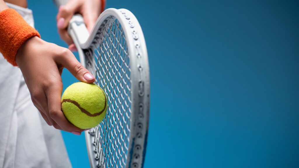 Teilansicht einer sportlichen jungen Frau mit Tennisschläger und Ball