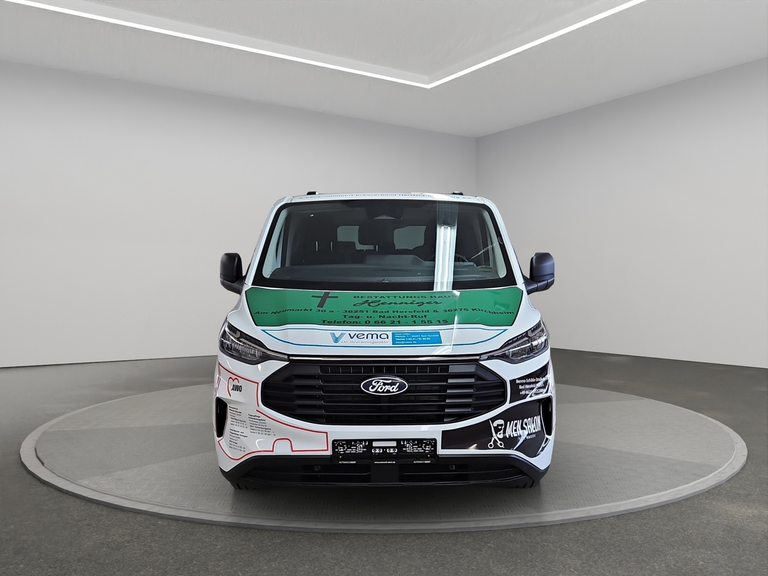 Ein weißer Ford Transit mit auffälligen bunten Werbeaufklebern steht in einem hellen Raum